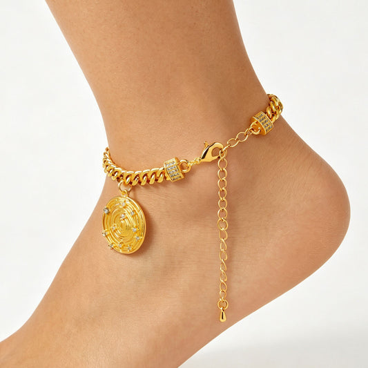 Gold-tone chain anklet with a round coin charm and clear accents