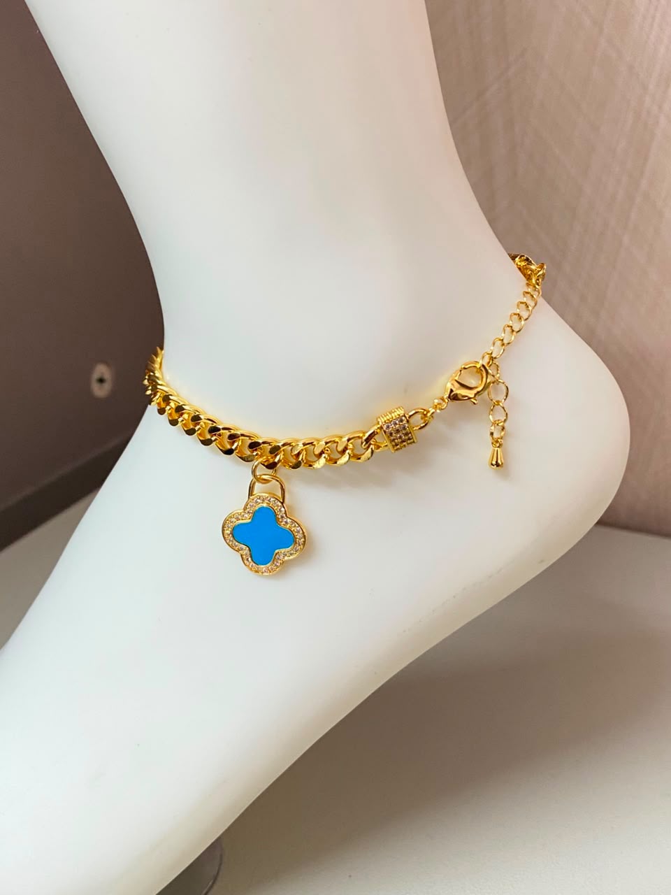 Gold-tone chain anklet with a blue clover charm and clear accents